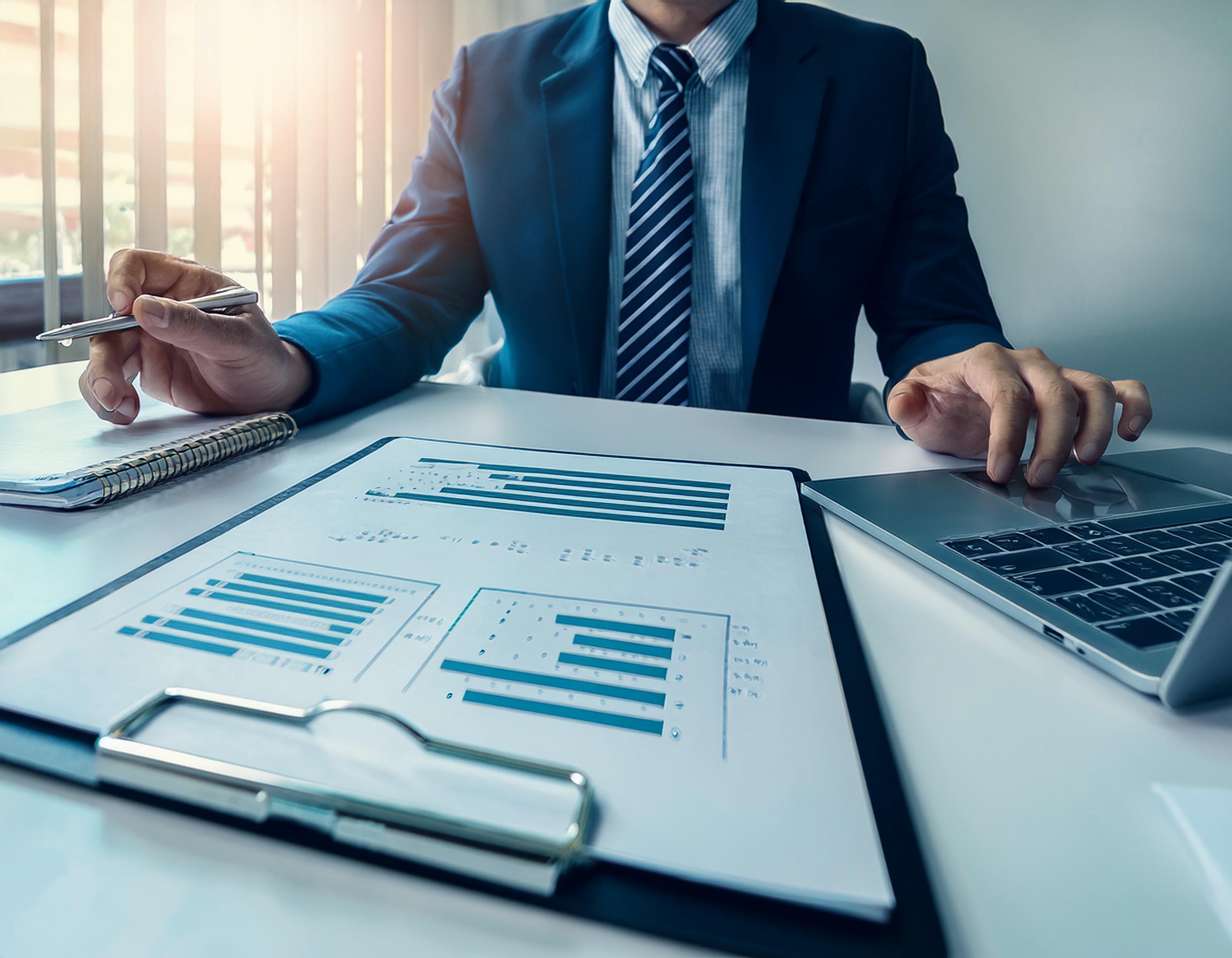 Steuerberater bei der Arbeit in einem eleganten Büro mit Akten und Laptop